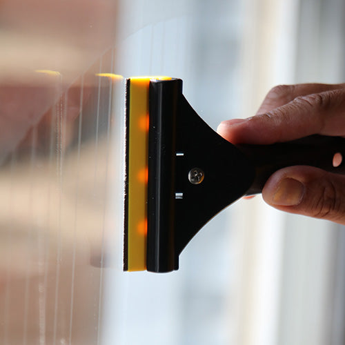 Professional window cleaning razor scraper removing paint from glass