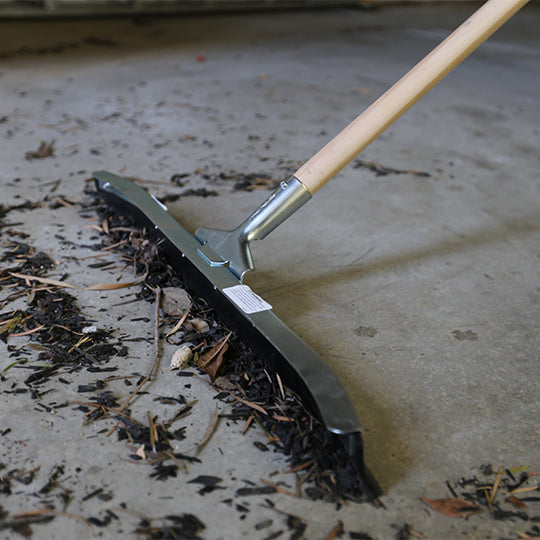 Heavy-duty floor squeegee moving debris across concrete surface